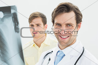 Smiling male doctor and patient examining lungs x-ray