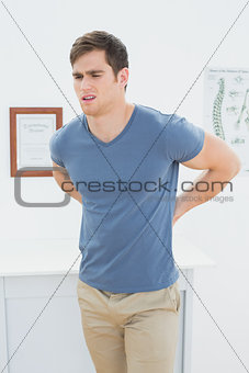 Handsome man with back pain in office