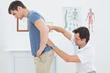 Male physiotherapist examining mans back in office