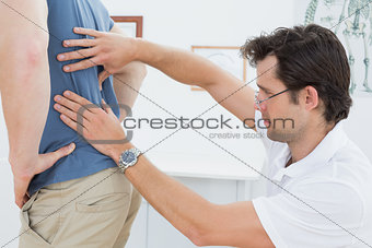 Side view of a male physiotherapist examining mans back