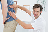 Portrait of a male physiotherapist examining mans back
