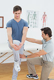 Male therapist assisting man with stretching exercises