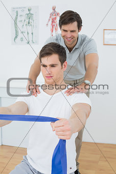 Male therapist assisting man with exercises in office