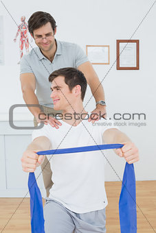 Male therapist assisting man with exercises in office
