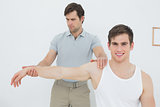 Male physiotherapist examining a young mans arm