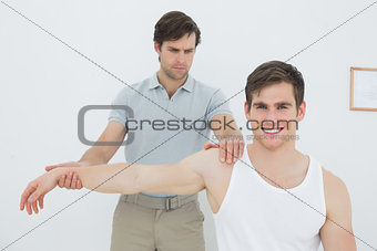 Male physiotherapist examining a young mans arm