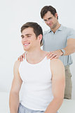 Male physiotherapist massaging a young mans shoulder