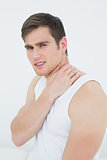 Side view portrait of a young man suffering from neck pain