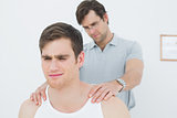 Male physiotherapist massaging a young mans shoulder