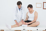 Full length of a young man getting his knee examined