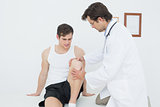 Displeased young man getting his knee examined