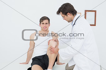 Portrait of a smiling young man getting his knee examined