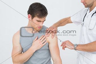 Male doctor injecting a young male patients arm