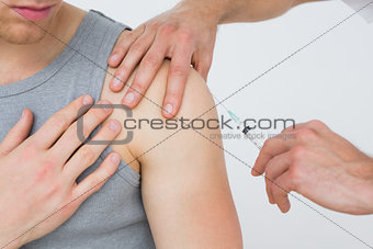 Close-up of hands injecting a young male patients arm