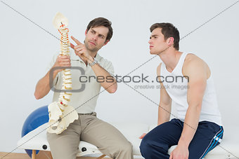 Physiotherapist showing patient something on skeleton model