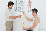 Physiotherapist showing patient something on skeleton model
