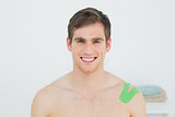 Handsome young man with green kinesio tape on shoulder