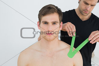 Physiotherapist putting on kinesio tape on patients shoulder