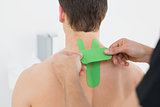 Physiotherapist putting on kinesio tape on patients back