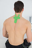 Shirtless man with green kinesio tape on back