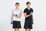 Portrait of two smiling young men with dumbbells