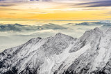 Scenic view of misty winter mountains with colorful sunset