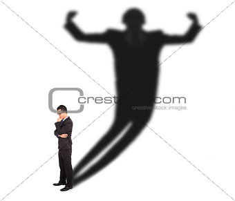 Business man standing and casting shadow of a strong man 