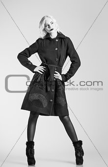 Studio fashion shot: beautiful girl in black coat and boots. Black and white 
