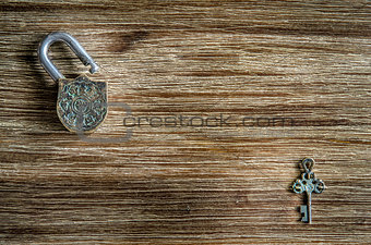 Open vintage padlock and key on a wooden texture