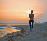 Fitness young woman running on beach in the evening