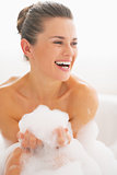 Smiling young woman in bathtub with foam
