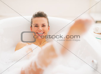 Smiling young woman having fun time in bathtub