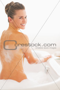 Happy young woman sitting in bathtub
