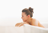 Young woman in bathtub looking on copy space