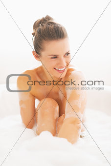 Smiling young woman sitting in bathtub