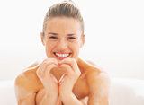 Happy young woman in bathtub showing heart with hands