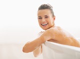Portrait of smiling young woman sitting in bathtub