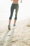 Closeup on fitness young woman running on beach
