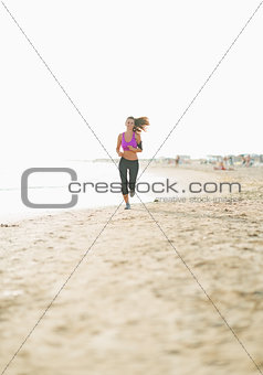 Fitness young woman running on beach