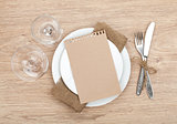 Blank paper on plate, wine glasses and silverware set