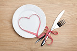 Valentine's Day heart shaped red ribbon over plate with silverwa