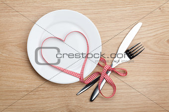 Valentine's Day heart shaped red ribbon over plate with silverwa