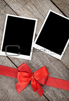 Two photo frames over wooden background with red bow