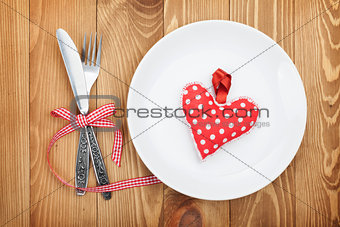 Valentine's Day toy heart over plate with silverware