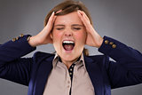 Angry businesswoman screaming and holding her head