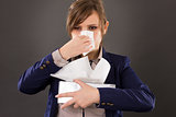 Portrait of a  young businesswoman with flu blowing her nose