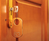 Door handles on wood wing of door and key in keyhole with number