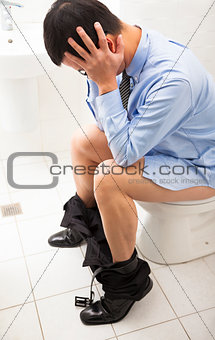 business man with frustrated expression sitting toilet seat