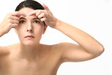 Young woman squeezing a pimple on her forehead