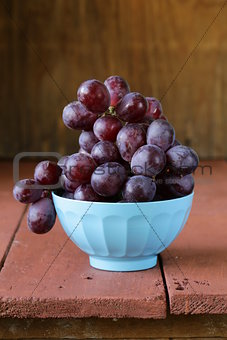 large ripe black grapes in a blue bowl